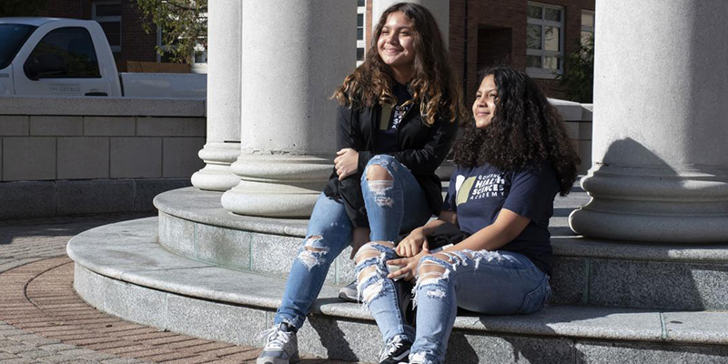 two girls sitting on a step on campus