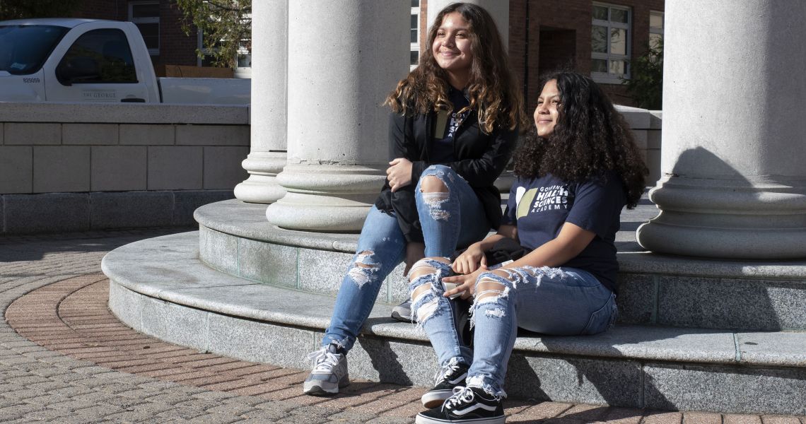 Two students sitting on a step on campus