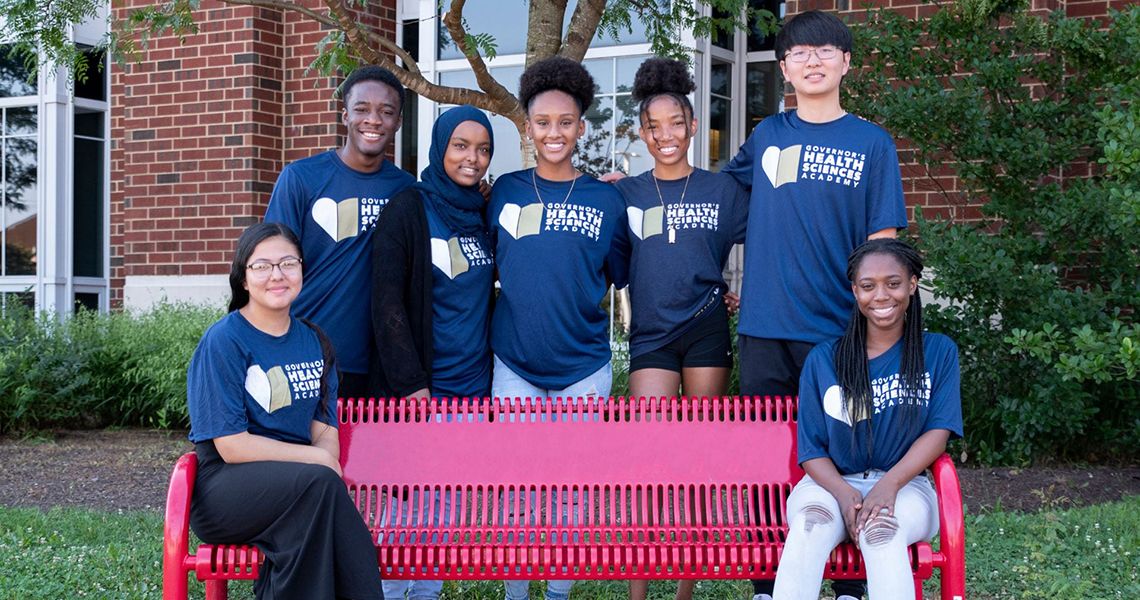 Students standing around and sitting on a bench