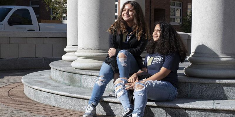 two girls sitting on a step on campus